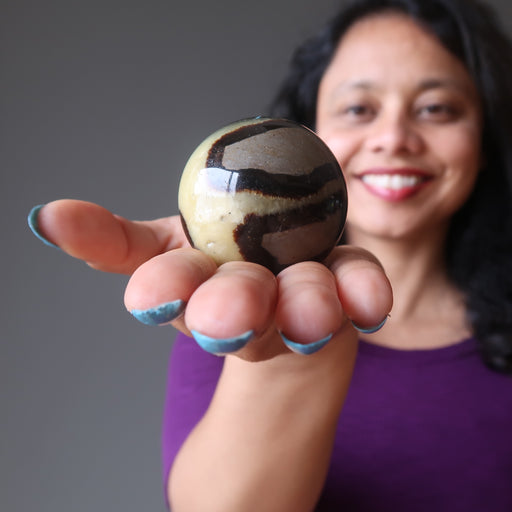 sheila of satin crystals holding out a septarian stone sphere