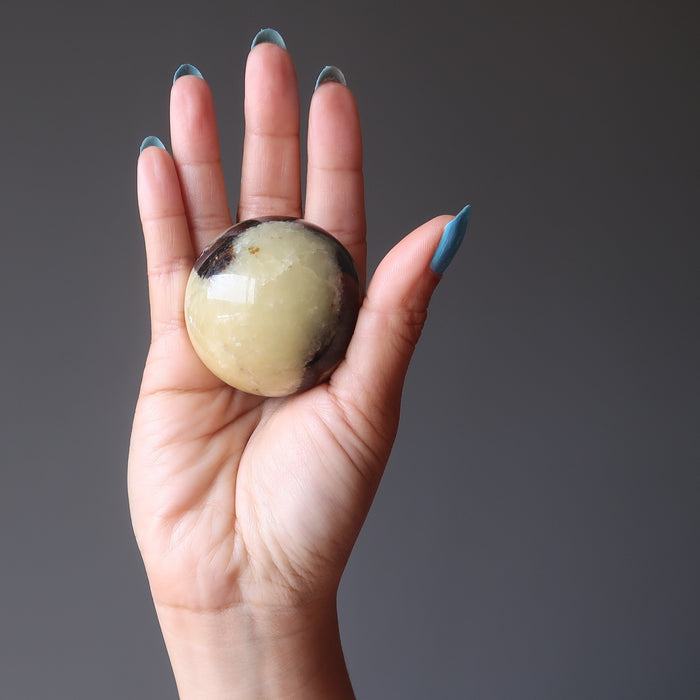 hand holding septarian sphere in palm