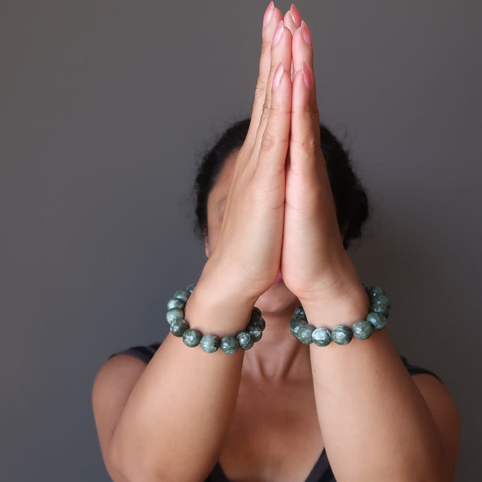 hands in prayer wearing hand wearing natural green seraphinite stretch bracelet