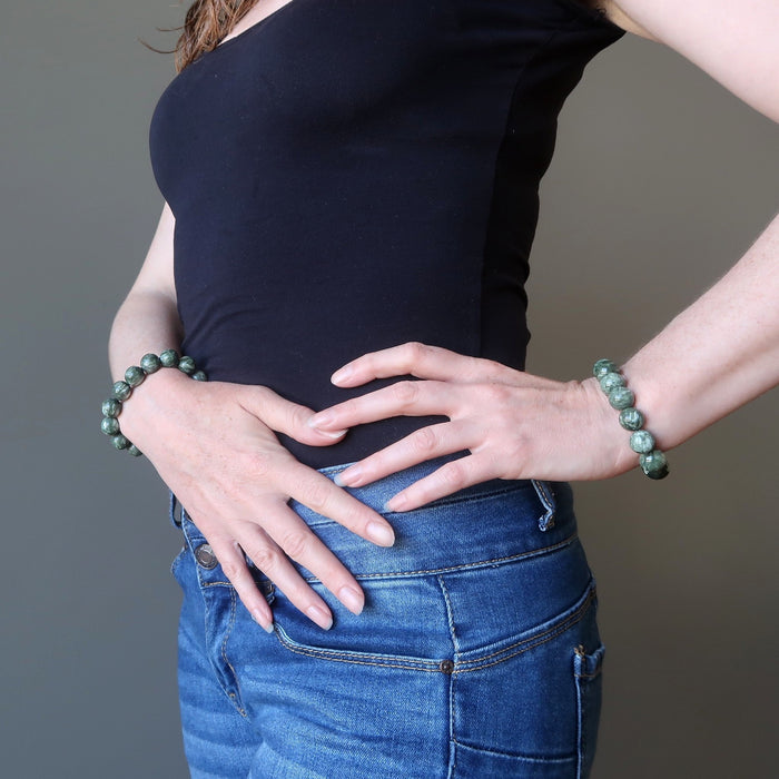 hands on hip wearing natural green seraphinite stretch bracelets