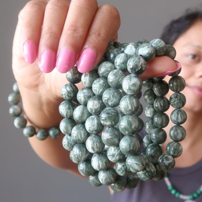 sheila of satin crystals holding  5 natural green seraphinite stretch bracelets