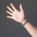 hand wearing natural green seraphinite stretch bracelet
