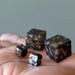 hand holding four silver and orange sericho meteorite cubes