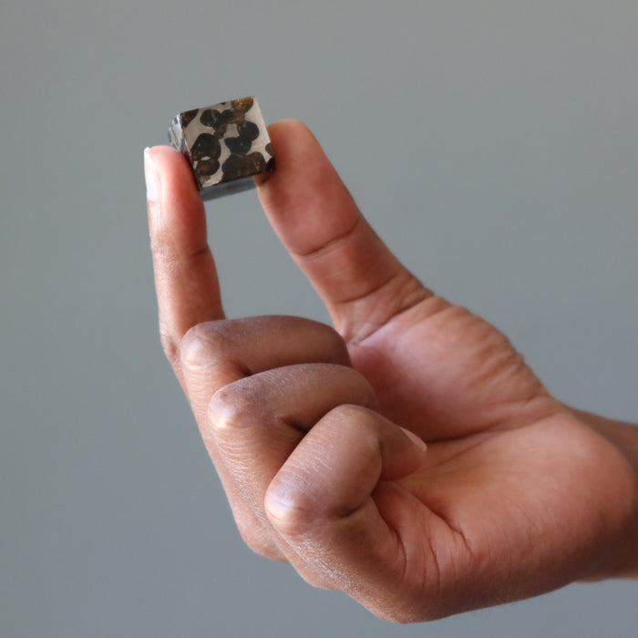 hand holding silver and orange sericho meteorite cube