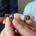 hands holding silver and orange sericho meteorite cubes