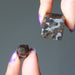 hands holding silver and orange sericho meteorite cubes