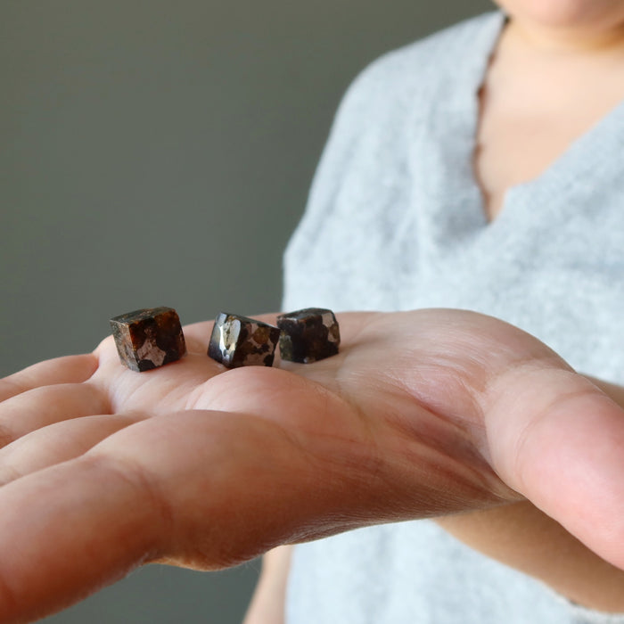 three silver and orange sericho meteorite cubes in palm of hand
