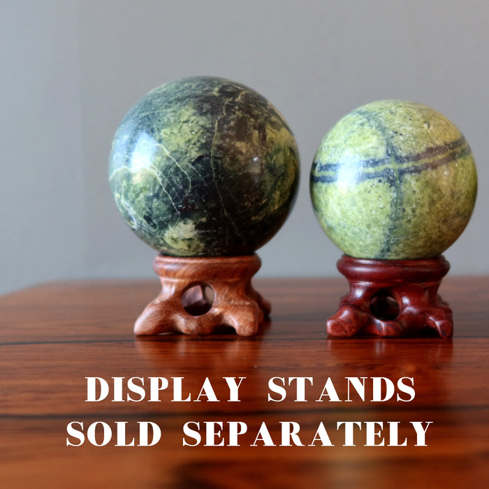 two serpentine spheres on wood stands, which are sold separately