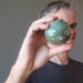 ryan of satin crystals holding  serpentine sphere to his eye