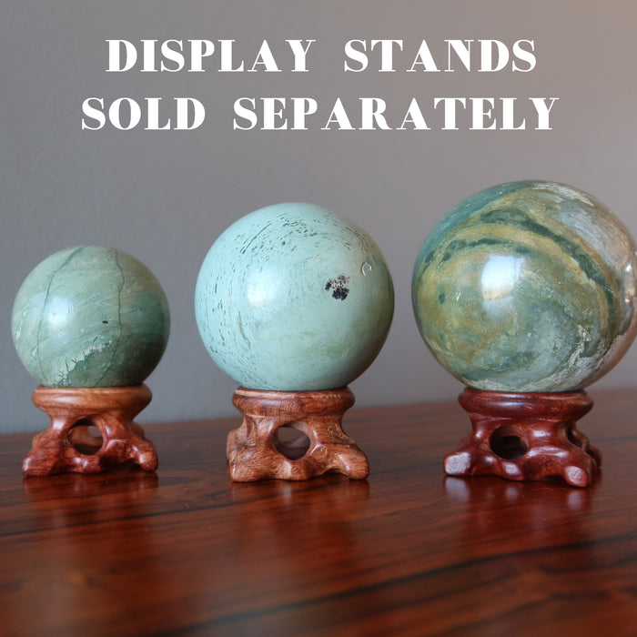 3 serpentine spheres on wood display stands, which are sold separately