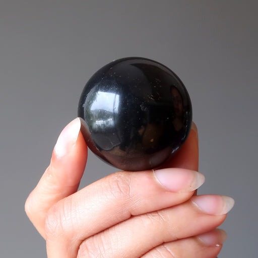 hand holding a shungite crystal sphere