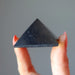 hand holding black shungite stone pyramid