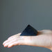 hand holding black shungite stone pyramid on palm