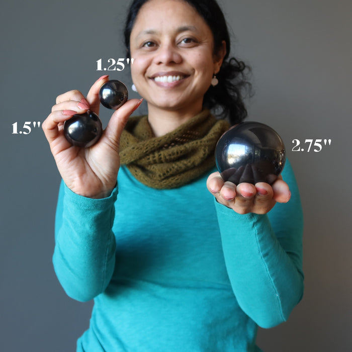 sheila holding 3 different sizes of Shungite Spheres