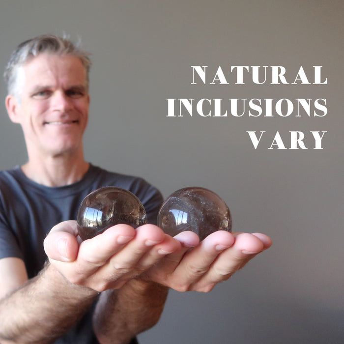 ryan of satin crystals holding two smoky quartz spheres showing natural inclusions vary