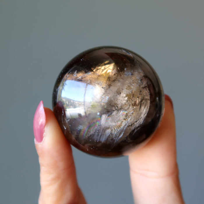 rainbow smoky quartz sphere in hand