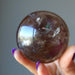 hand holding rainbow smoky quartz sphere