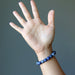 model raising hand wearing faceted round beaded sodalite bracelet on wrist