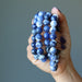 hand holding 4 faceted round beaded sodalite bracelets