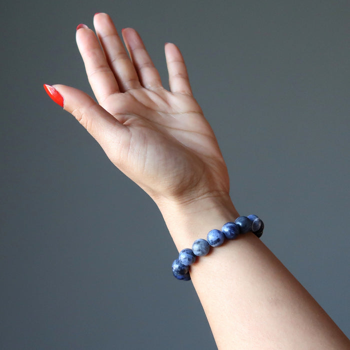 blue sodalite bracelet on the wrist of a lady with red nail polish