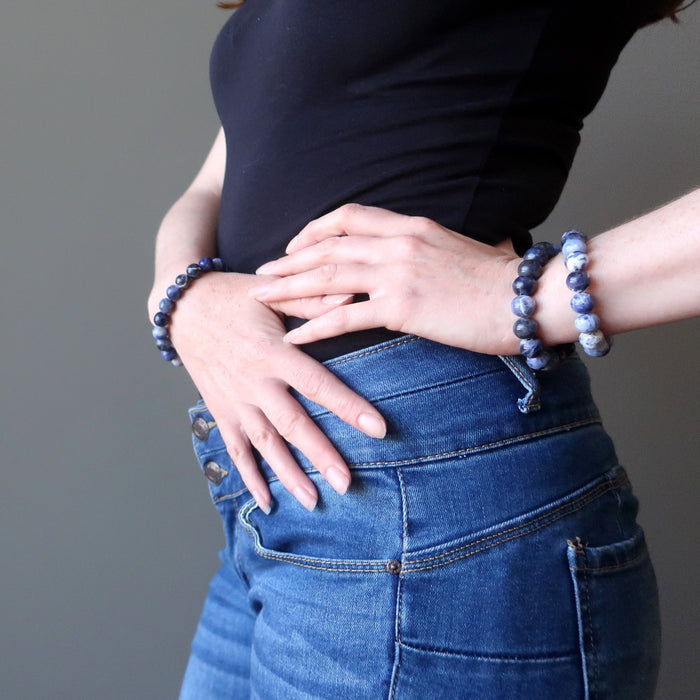 lady modeling three sodalite crystal healing bracelets on her wrists while holding her hands to her hips