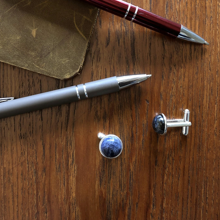 flatlay of blue sodalite silver cufflinks on table with pen and notebook