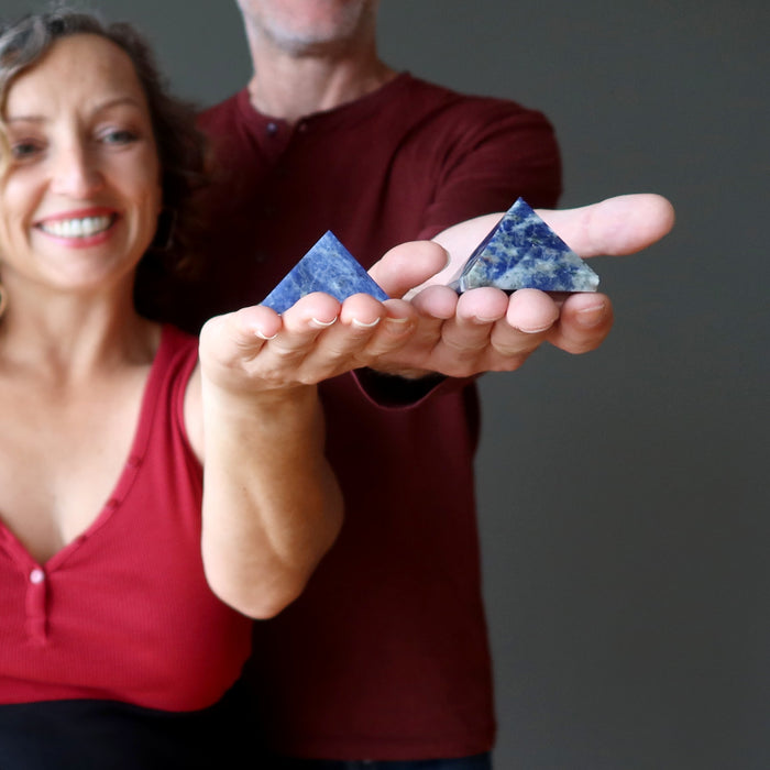 man and woman holding sodalite pyramids
