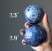 hand holding blue sodalite spheres showing size difference