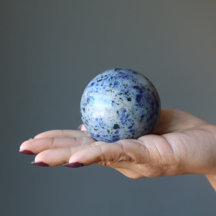 hand holding hand holding blue sodalite sphere
