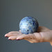 hand holding hand holding blue sodalite sphere