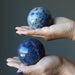 hand holding blue sodalite spheres in palms of hands