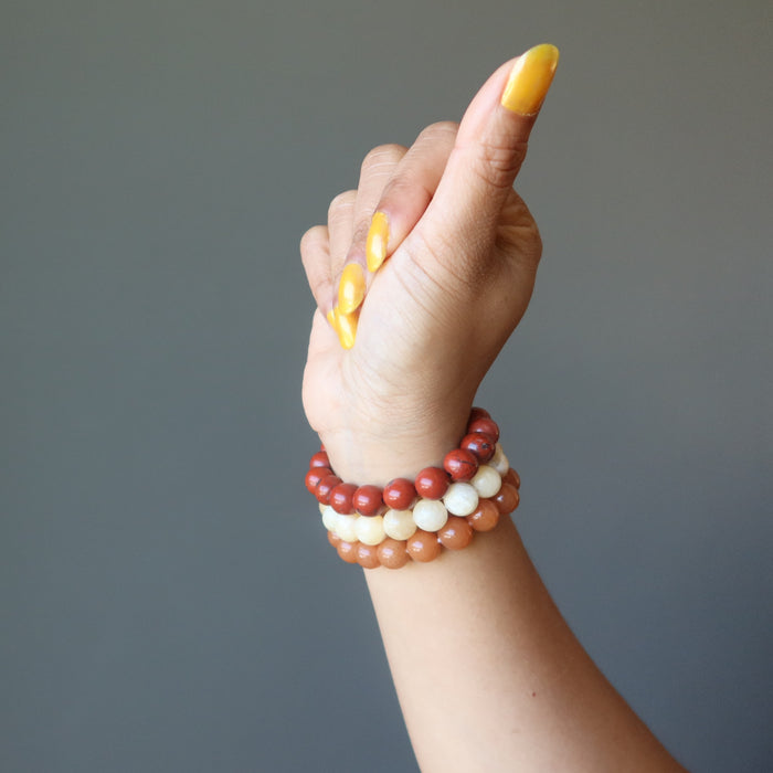 hand wearing yellow calcite, orange aventurine, red jasper stretch bracelet set