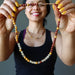 sheila of satin crystals holding up a red jasper, yellow jasper and citrine beaded necklace