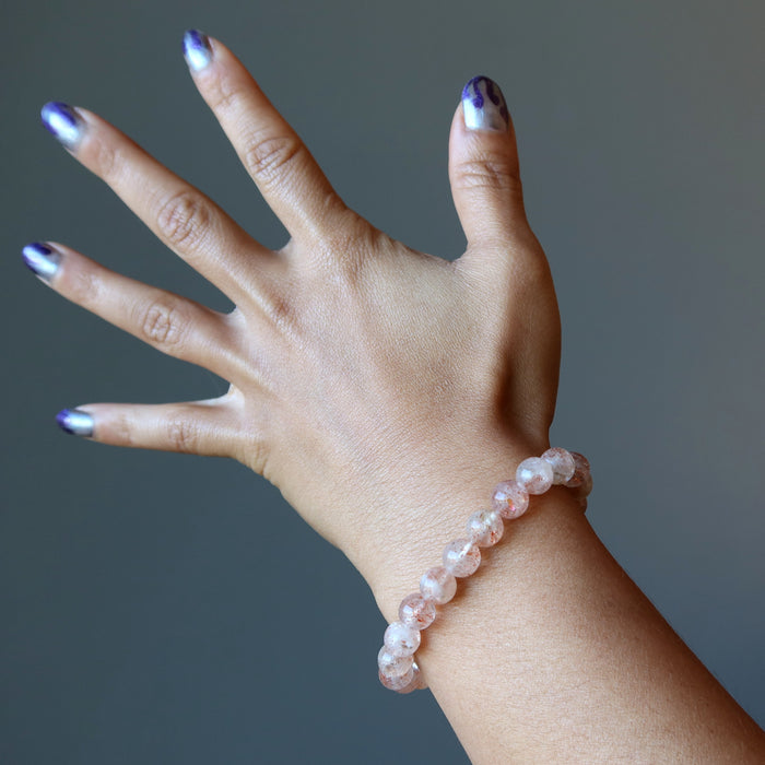 beaded red sunstone gem bracelet on hand model with blue nailpolish