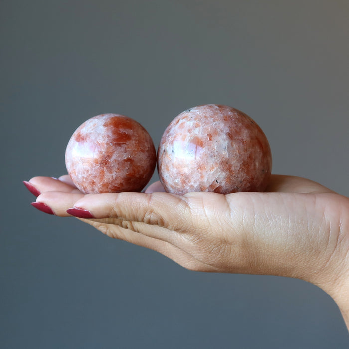 hand holding two sunstone sphere