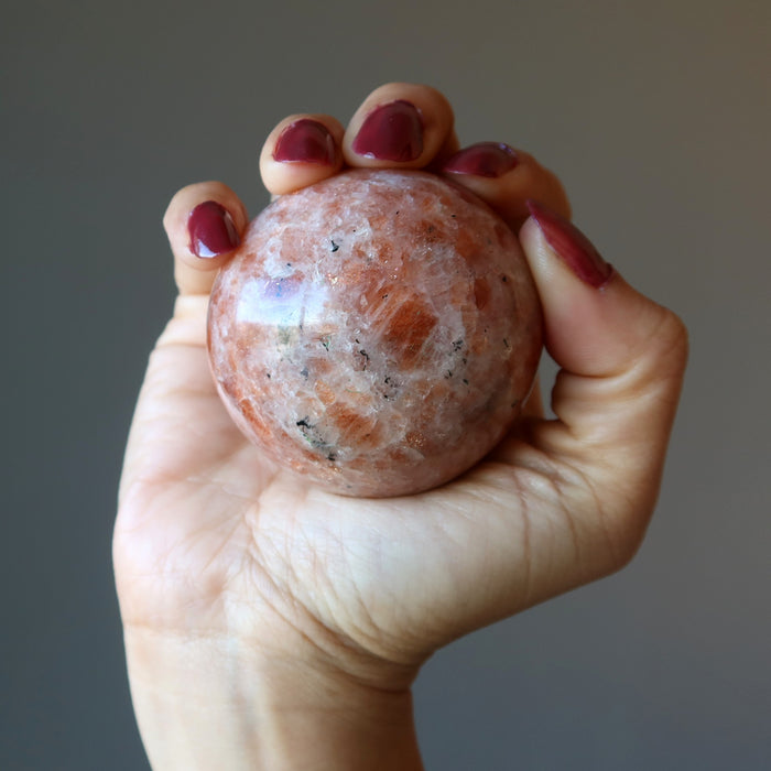 hand holding up a sunstone sphere