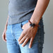 man with hands in pocket wearing tektite obsidian bracelet