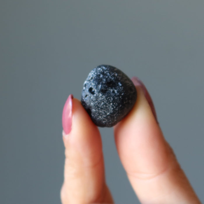 holding one holding a black Tektite Meteorite