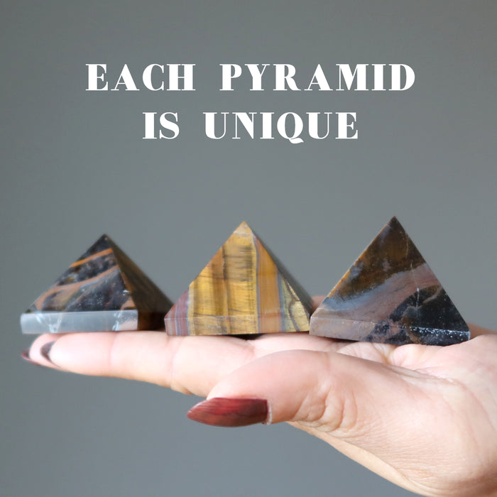 hand holding three tiger iron pyramids