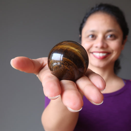 sheila of satin crystals holding out a golden tigers eye sphere