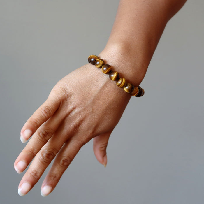 hand wearing golden brown tigers eye round stretch bracelet