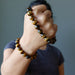 fist wearing two golden brown tigers eye round stretch bracelet