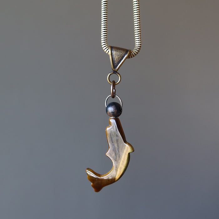 backside of tigers eye dolphin and black ball pendant on thick metal necklace