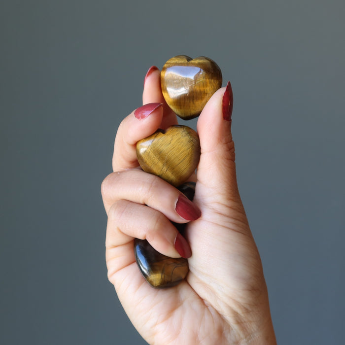 hand holding golden tigers eye hearts