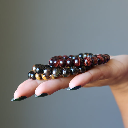 red, golden, and blue tigers eye beaded stretch bracelet set on palm of hand