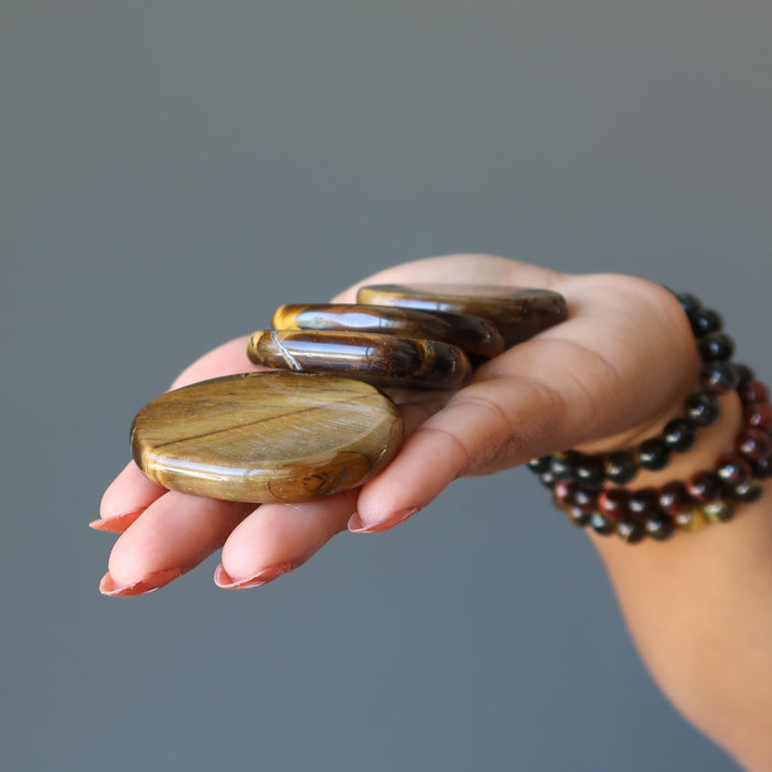 holding 4 tigers eye slabs on the palm