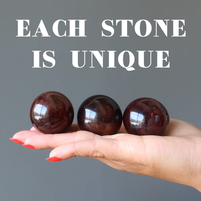 hand holding red tigers eye spheres to show each is unique