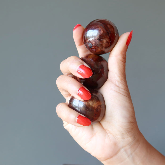 hand holding red tigers eye spheres