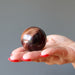 hand holding red tigers eye sphere