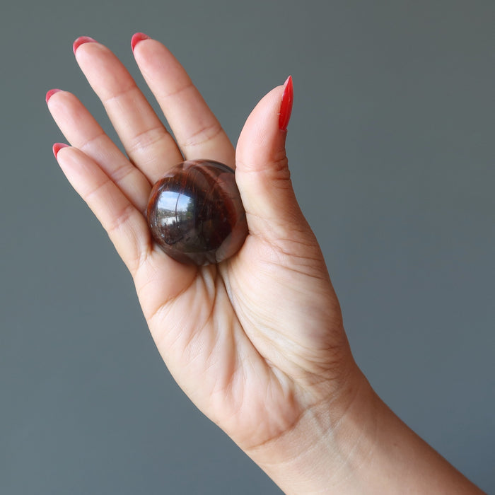 hand holding red tigers eye sphere